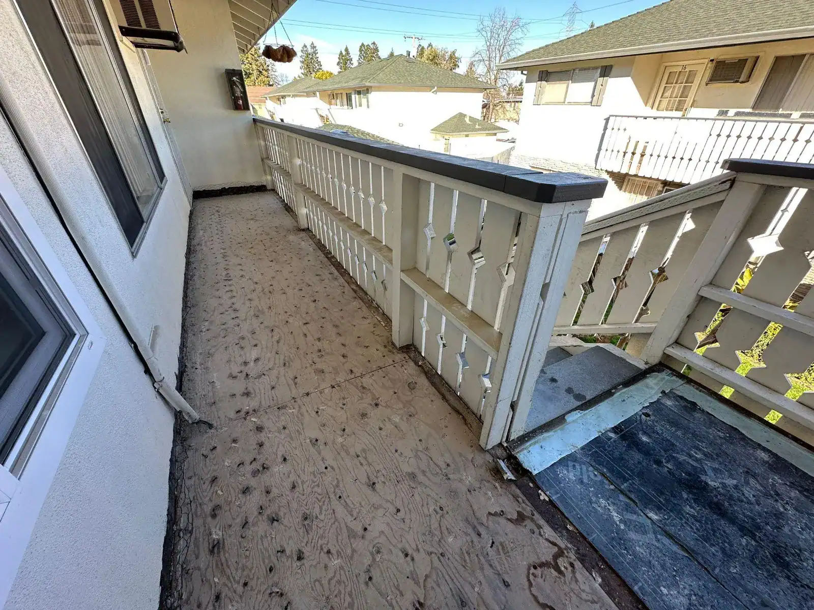 Apartment balcony stripped to bare plywood decking during a California waterproofing repair