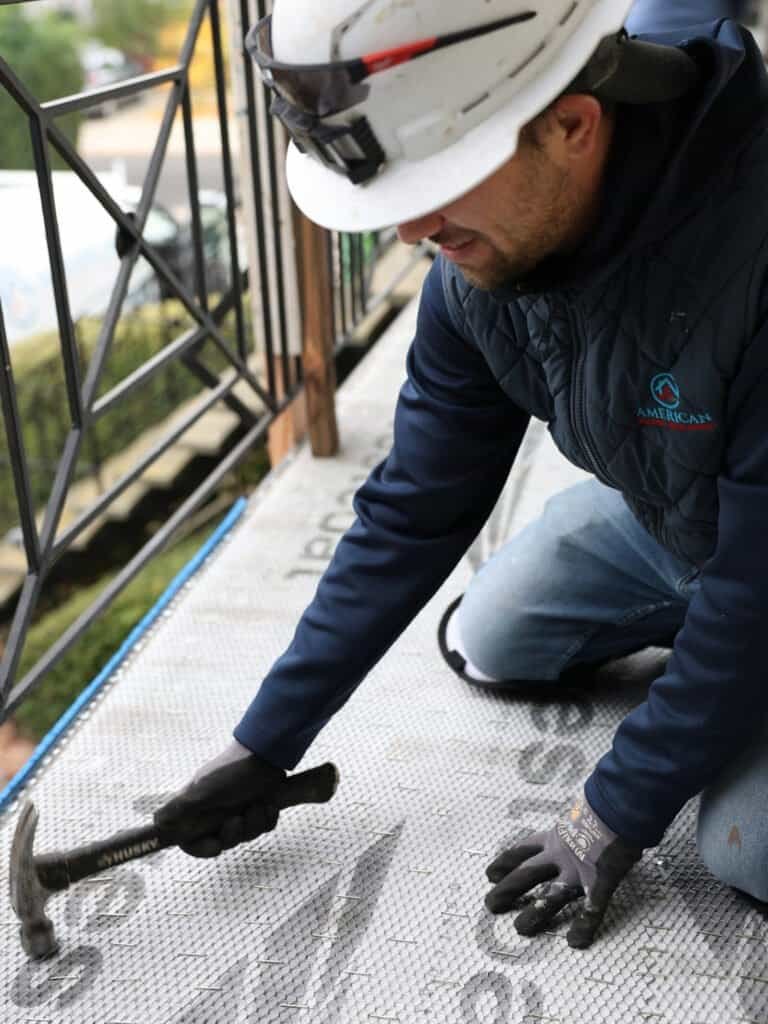 Licensed contractor inspecting balcony waterproof membrane on an HOA condo building