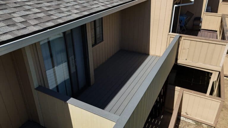 Composite decking and light grey cap rail seen from above on a rebuilt townhome balcony