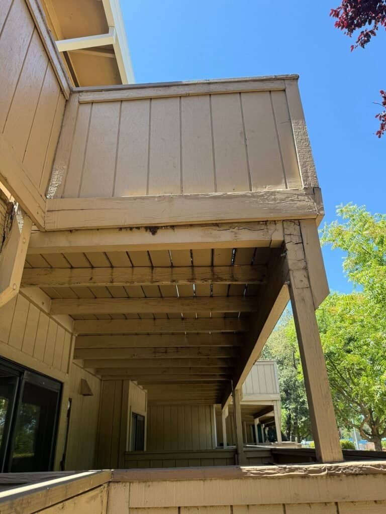 Dry rot along the beam and a split post under a townhome balcony in Antelope before repair