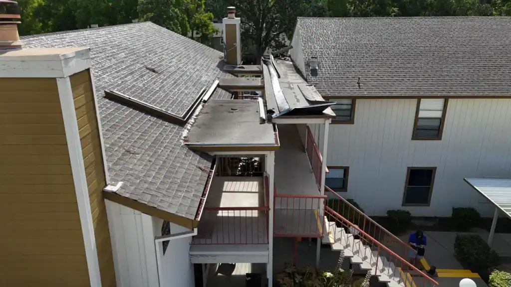Aerial view of a failed low-slope walkway roof in Citrus Heights with edge metal peeled loose from the membrane