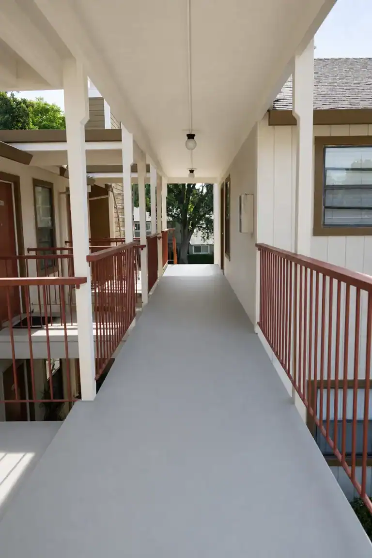 Rebuilt second-floor apartment walkway in Citrus Heights with new grey waterproof deck coating and freshly painted ceiling and posts