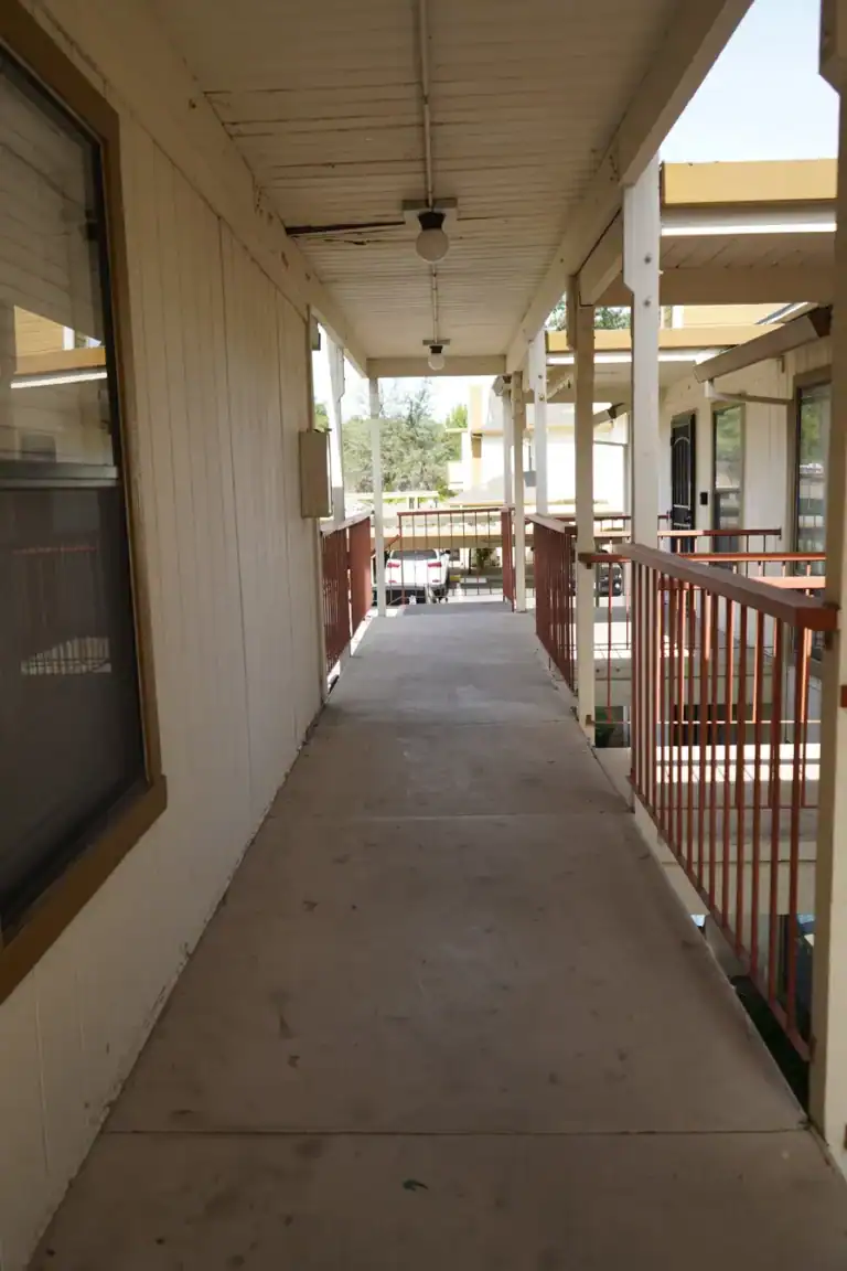 Water staining across the walkway ceiling and weathered beams before repair