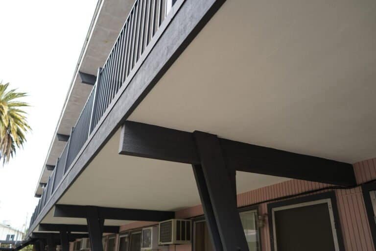 New drip edge and repainted steel support beams under a rebuilt apartment walkway