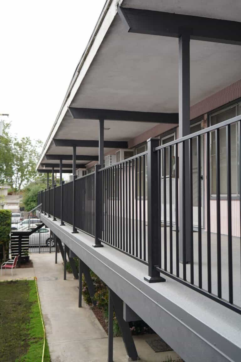 Rebuilt apartment walkway seen from the courtyard with new railings and painted structure