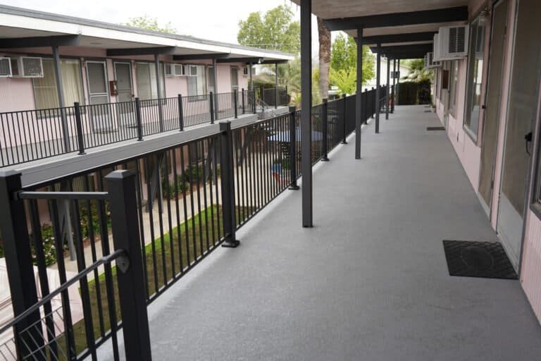 Full length of a rebuilt second-floor apartment walkway with new coating and guardrails in Lodi