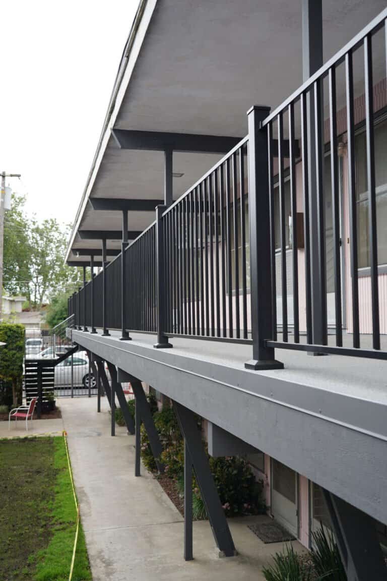 Rebuilt second-floor apartment walkway in Lodi with new waterproof deck coating and black aluminum guardrail
