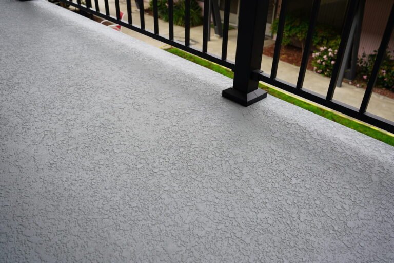 Textured non-slip waterproof deck coating and railing post base plate on a rebuilt apartment balcony