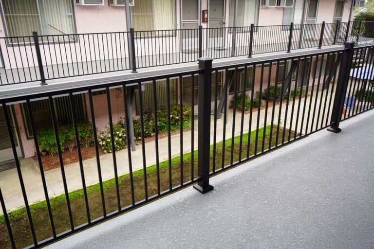 Two rebuilt walkway runs with matching guardrails across an apartment courtyard