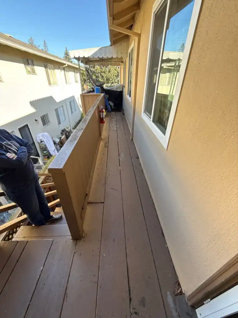 Worn painted wood walkway with a solid wood knee-wall guard at a Menlo Park apartment building before replacement