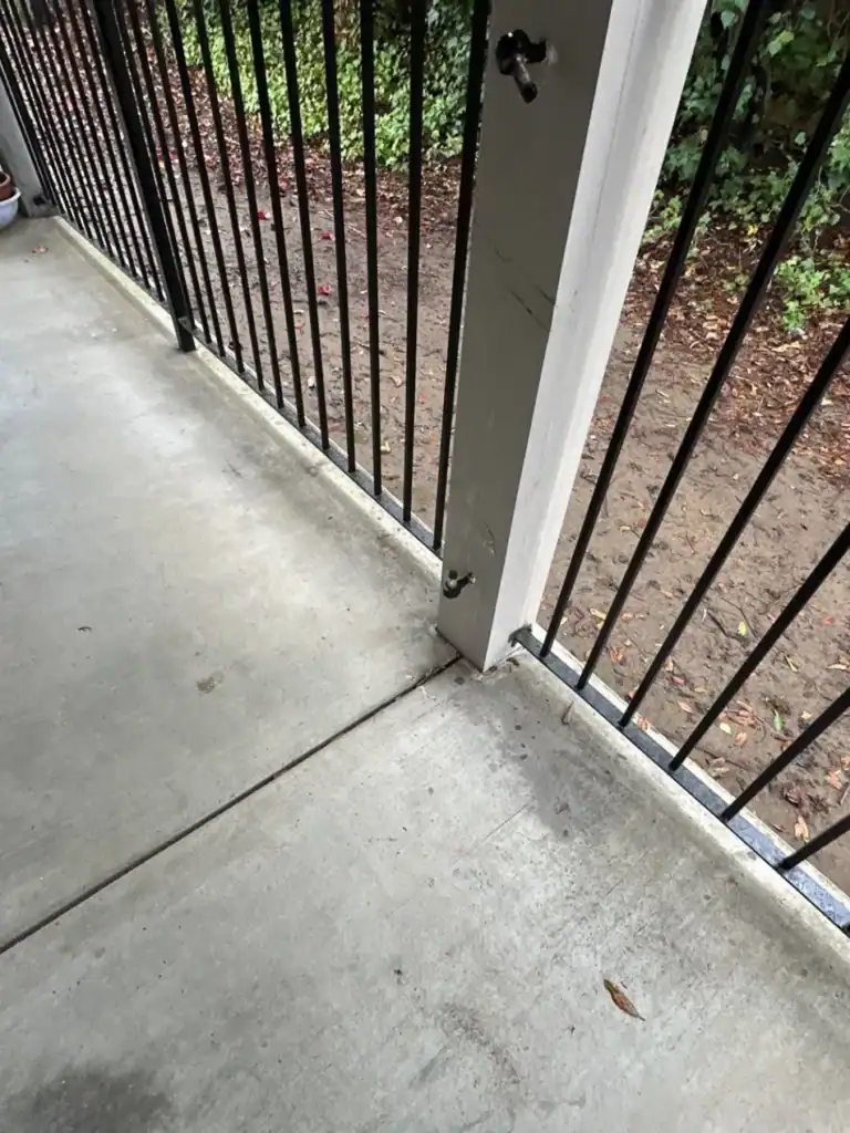 Cracked walkway surface at a post base before waterproofing