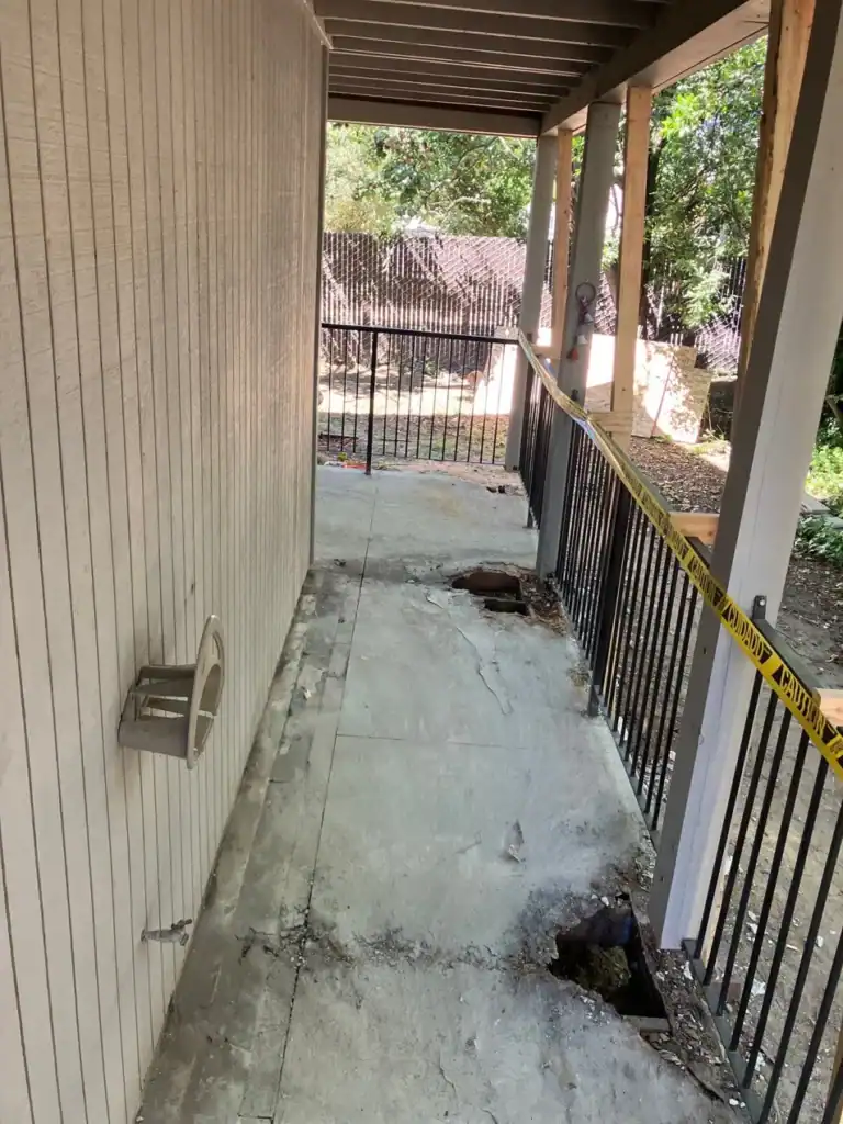 Holes broken through a lightweight concrete apartment walkway exposing rotted wood framing in Rio Linda