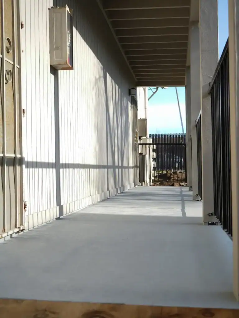 Low view along a freshly coated apartment walkway with black picket railing