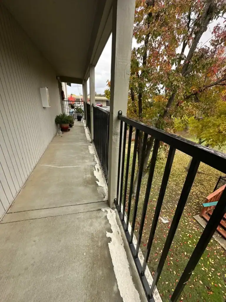 Peeling coating along the edge of an elevated apartment walkway before waterproofing