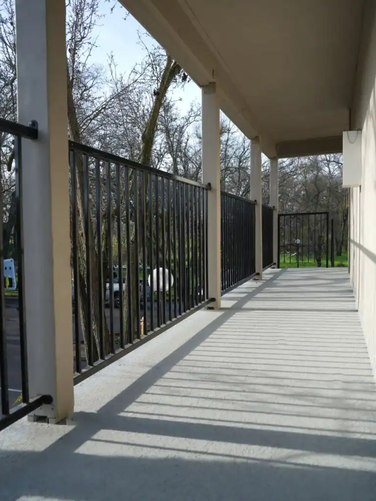 Rebuilt apartment walkway in Rio Linda with new textured waterproof deck coating and black guardrail