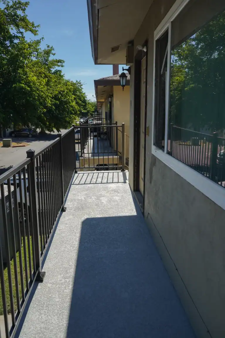 Reconstructed entry balcony in Sacramento with new grey waterproof deck coating and black aluminum guardrail