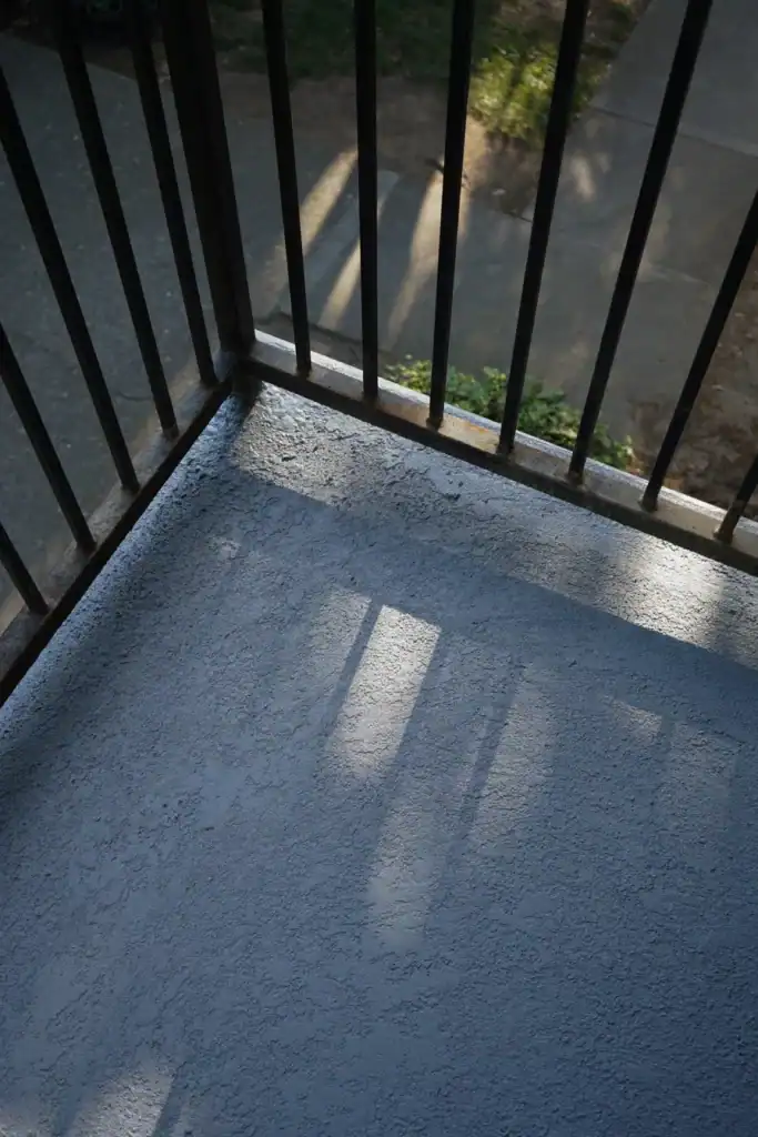 The same balcony corner after elastomeric coating, sealed around the railing base and turned over the edge