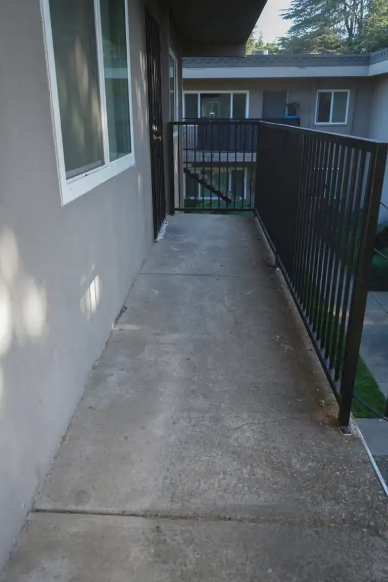 Bare concrete walkway serving upper-floor apartments before a waterproof coating was applied