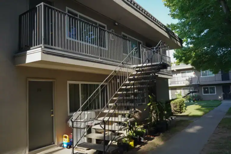 Two-story apartment building with coated upper walkway and repainted balcony edge