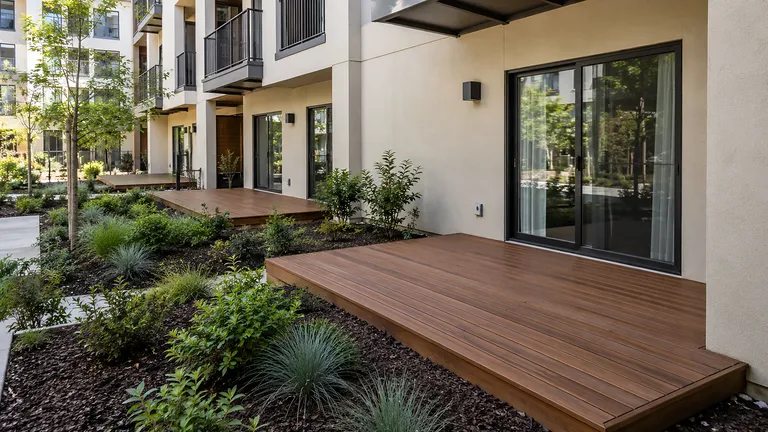 Deck installation service Sacramento — finished hardwood-tone composite deck at a courtyard-facing ground-floor unit