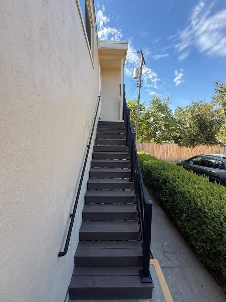 Elk Grove apartment stair with Trex composite treads, open risers and a black aluminum guardrail