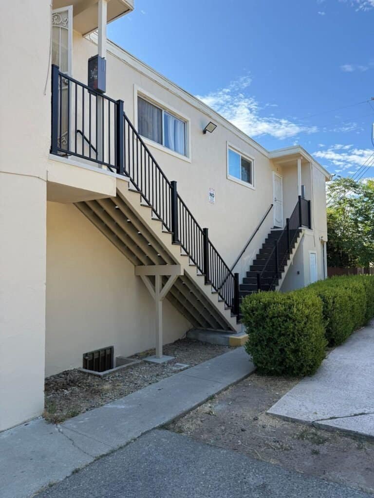 Two-story Elk Grove apartment building with rebuilt exterior stairs in Trex composite and black aluminum guardrails