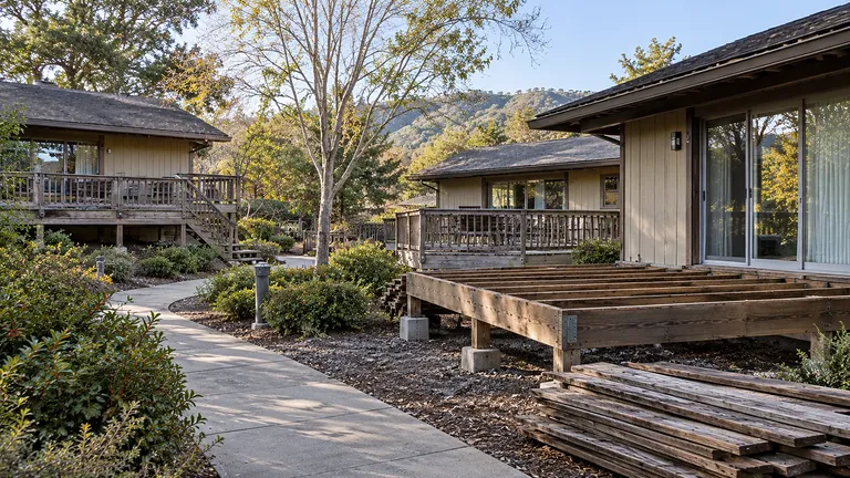 Residential community cottages with private decks, one stripped to the framing during the rebuild program