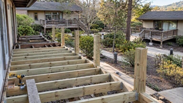 New deck framing with pressure-treated joists and guardrail posts set on structural connectors