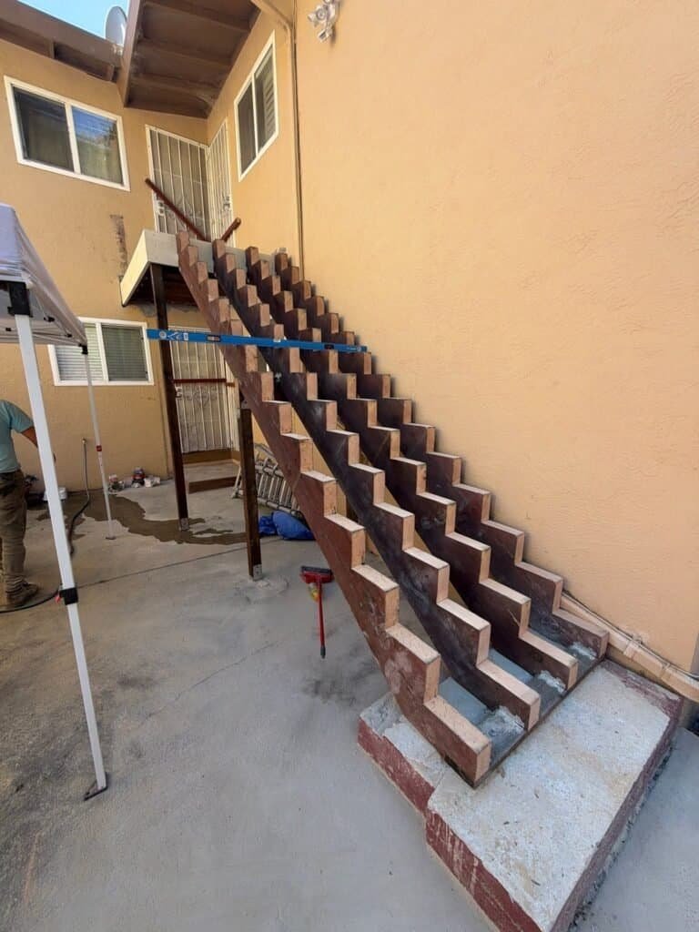 Apartment stair stringers stripped bare and re-cut, with new base connectors at the concrete pad