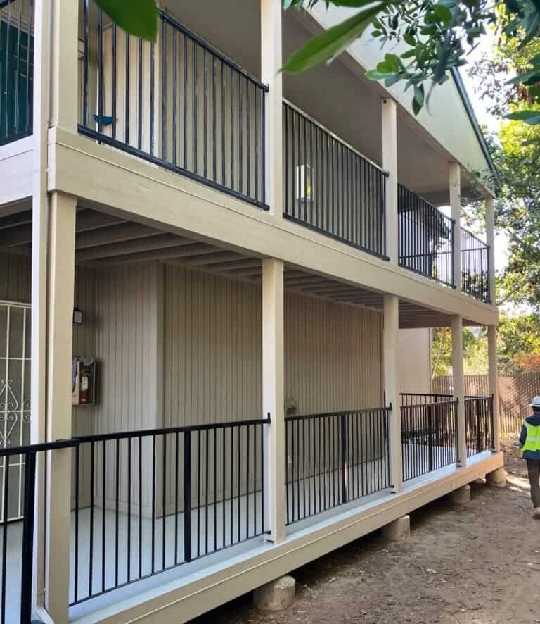 Two-story Rio Linda apartment building with rebuilt balcony framing, new fascia and black aluminum guardrails after waterproofing
