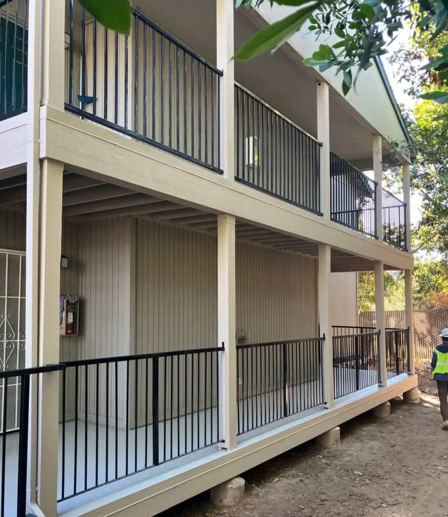Two-story Rio Linda apartment building with rebuilt balcony framing, new fascia and black aluminum guardrails after waterproofing