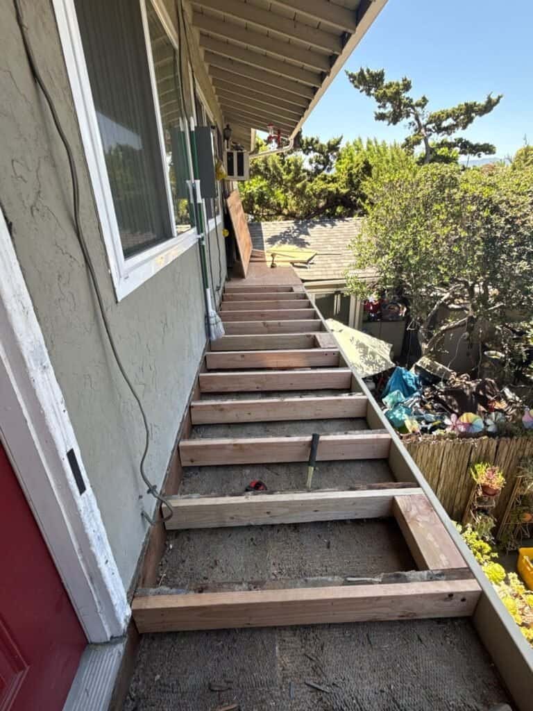 San Jose apartment walkway stripped to the joists, with new pressure-treated framing laid before waterproofing