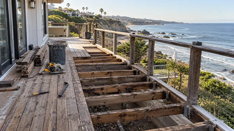Deck boards removed exposing water-darkened joists during an ocean-view deck replacement