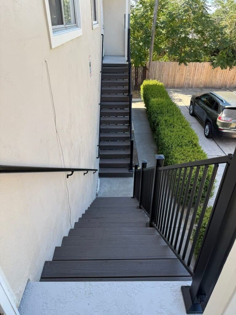 Looking down a rebuilt Elk Grove apartment stair from the upper landing, composite treads and aluminum guard