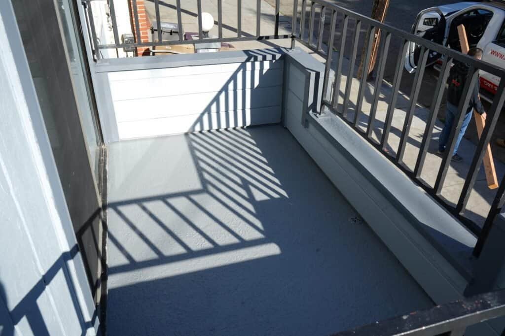 Recoated apartment balcony in Vacaville showing the re-flashed deck drain and repainted guard wall