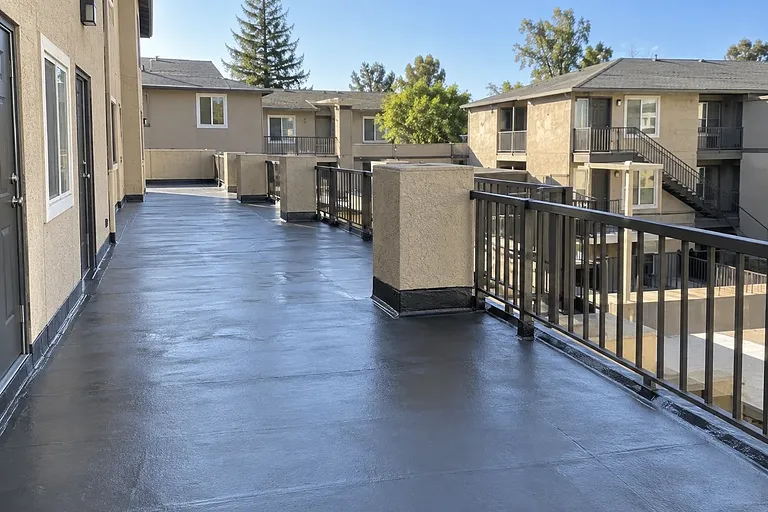 Sacramento waterproofing contractors — recoated condominium walkway with guardrail and coved base