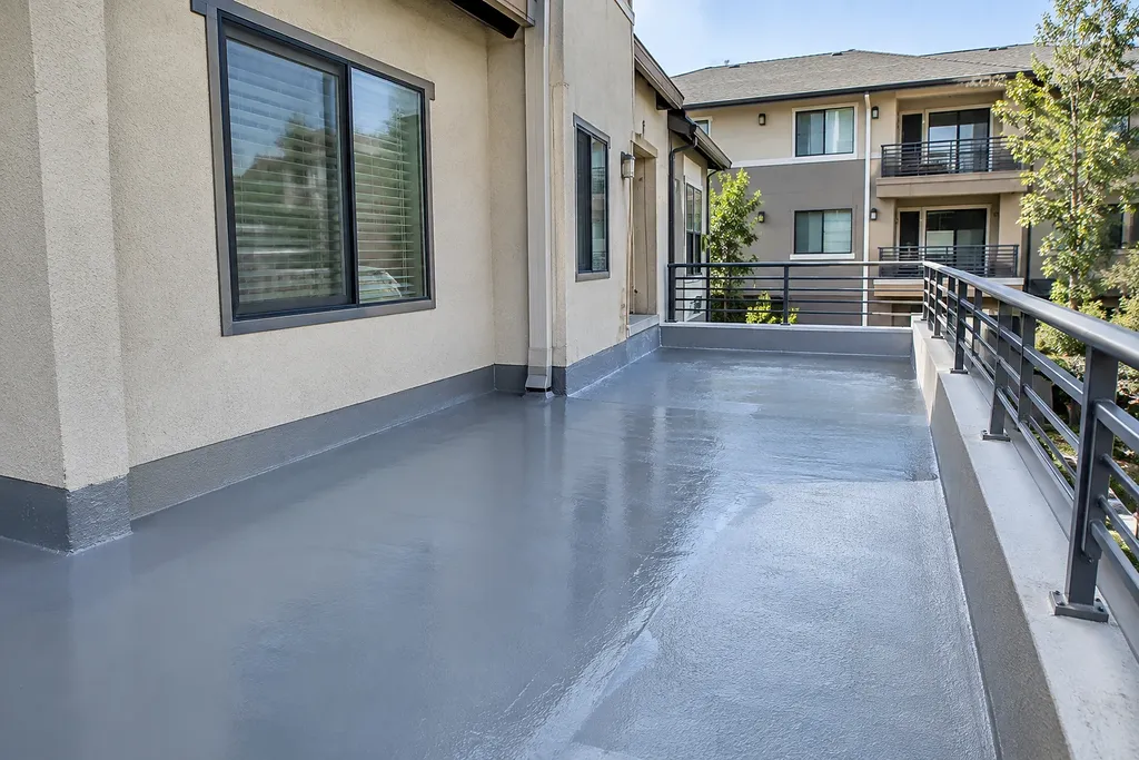 Sacramento waterproofing — coated balcony deck with coved wall base and fascia-mounted guardrail