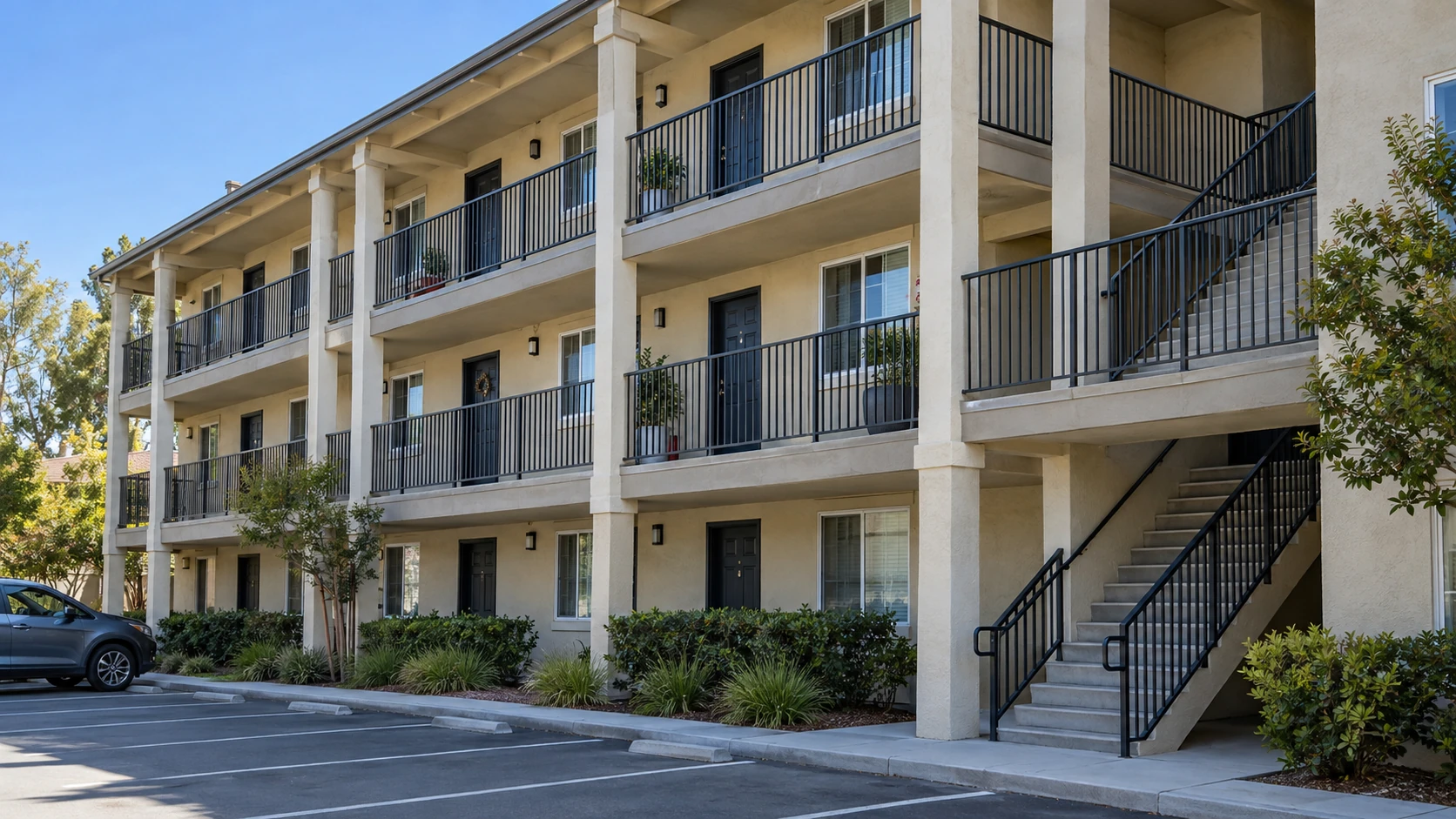 Three-story apartment building with railings along its balconies, walkways, and stairs