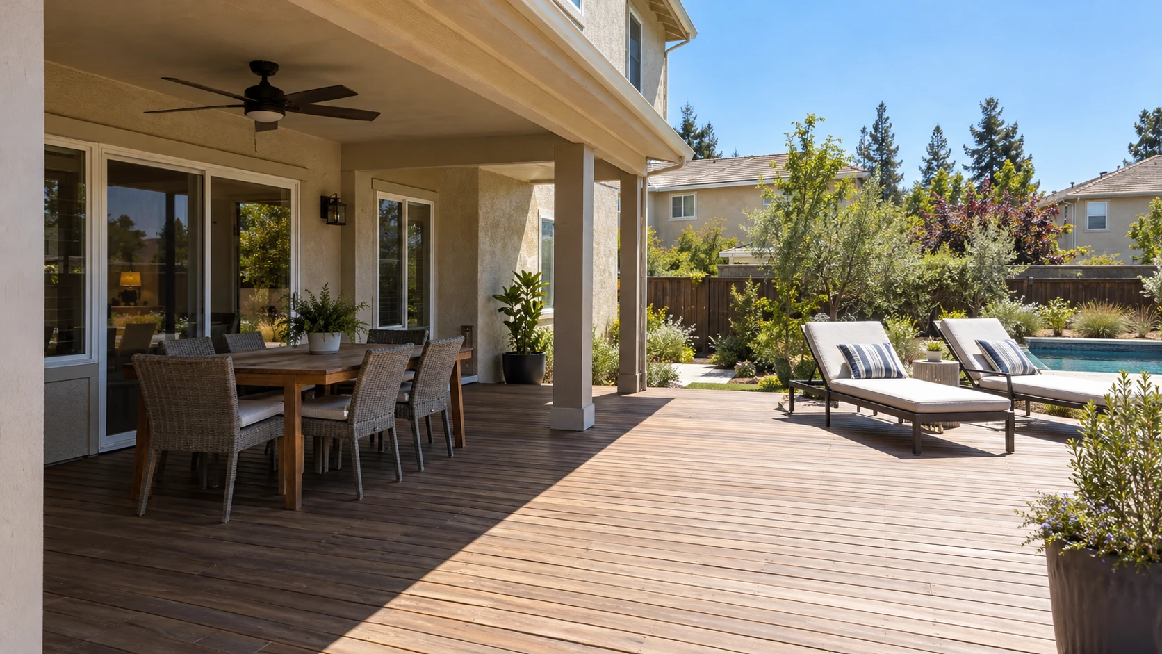 Covered dining area on a wood deck beside a backyard pool