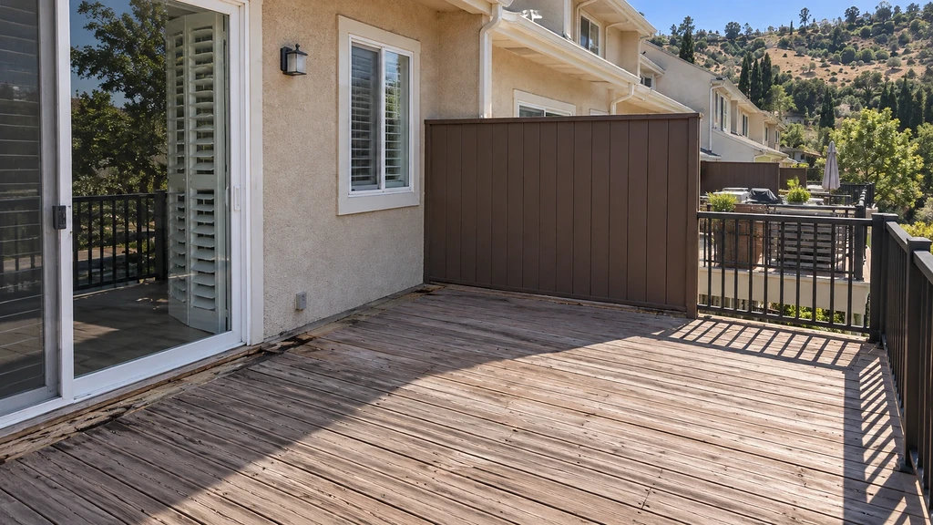 Weathered wood balcony decking with split, decayed boards along the sliding-door sill before replacement in Morgan Hill