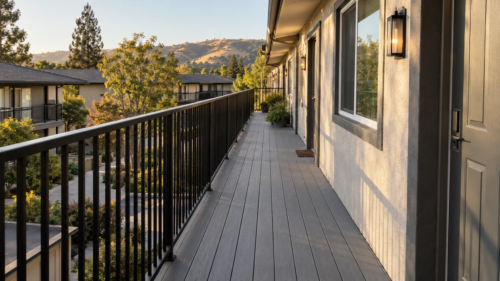 Gray composite decking on an apartment building's exterior walkway with a black metal railing