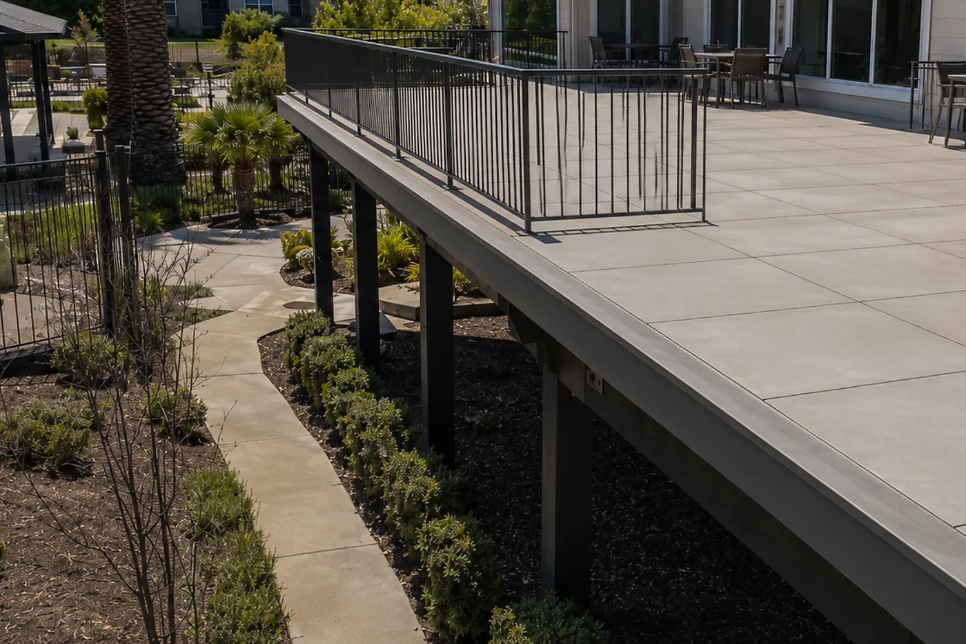 Elevated common-area apartment deck re-waterproofed with a continuous membrane and pedestal pavers, joists saved