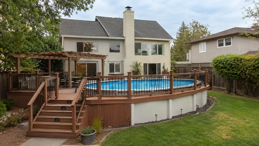 Finished above-ground pool deck with guardrails, stairs and lighting around the water