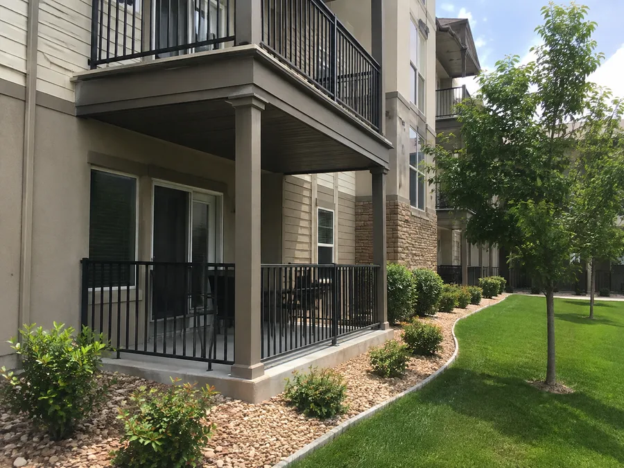 Ground-floor covered patio beneath an apartment balcony, with columns and a finished soffit