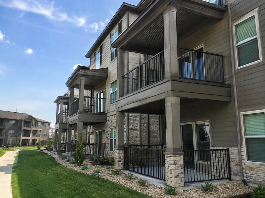 Apartment building with covered balconies carried on columns above ground-floor patios