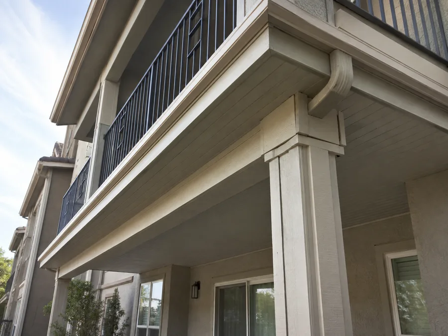 Underside of a covered apartment balcony showing the soffit, beam and downspout