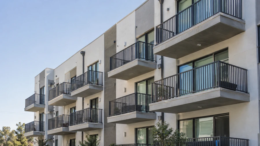 Stucco multi-unit building with black metal balcony railings on three floors