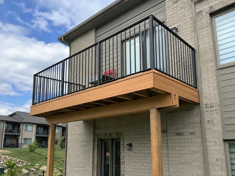 Completed balcony extension with cedar fascia and black metal guardrails