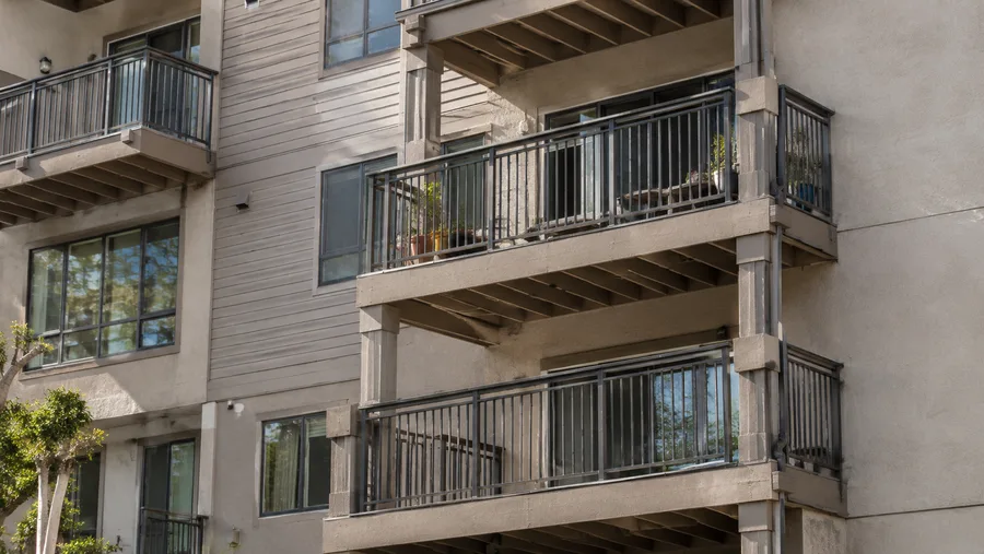 Stacked condominium balconies with metal guardrails and exposed wood framing beneath the decks