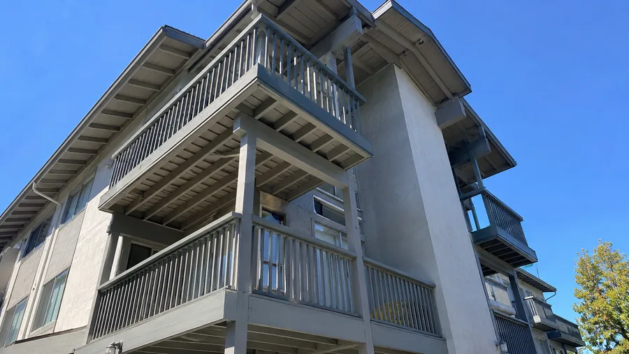 Weathered wood balconies and guardrails on an older California condominium building